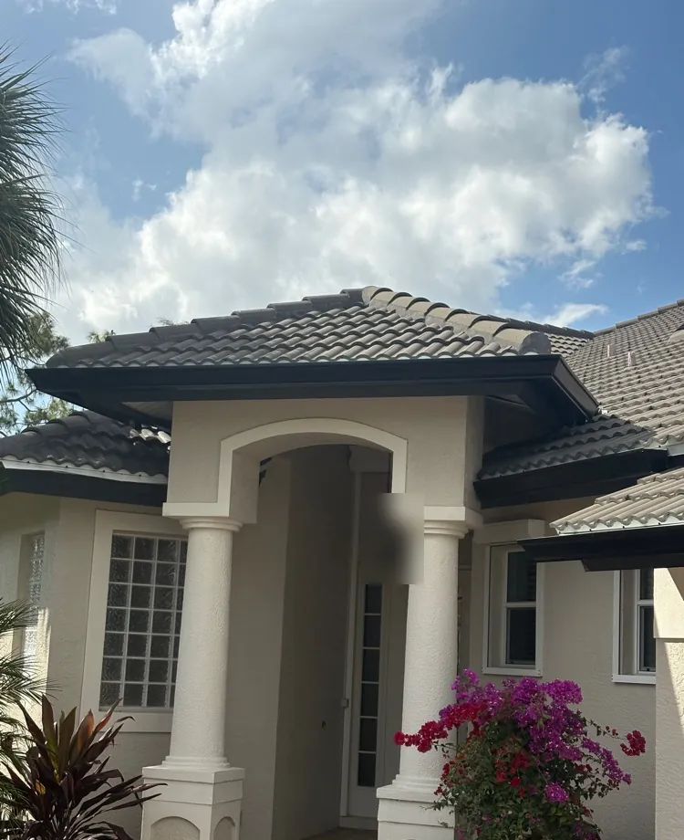 Black gutters on a tile-roof home with a columned entry in Estero, FL