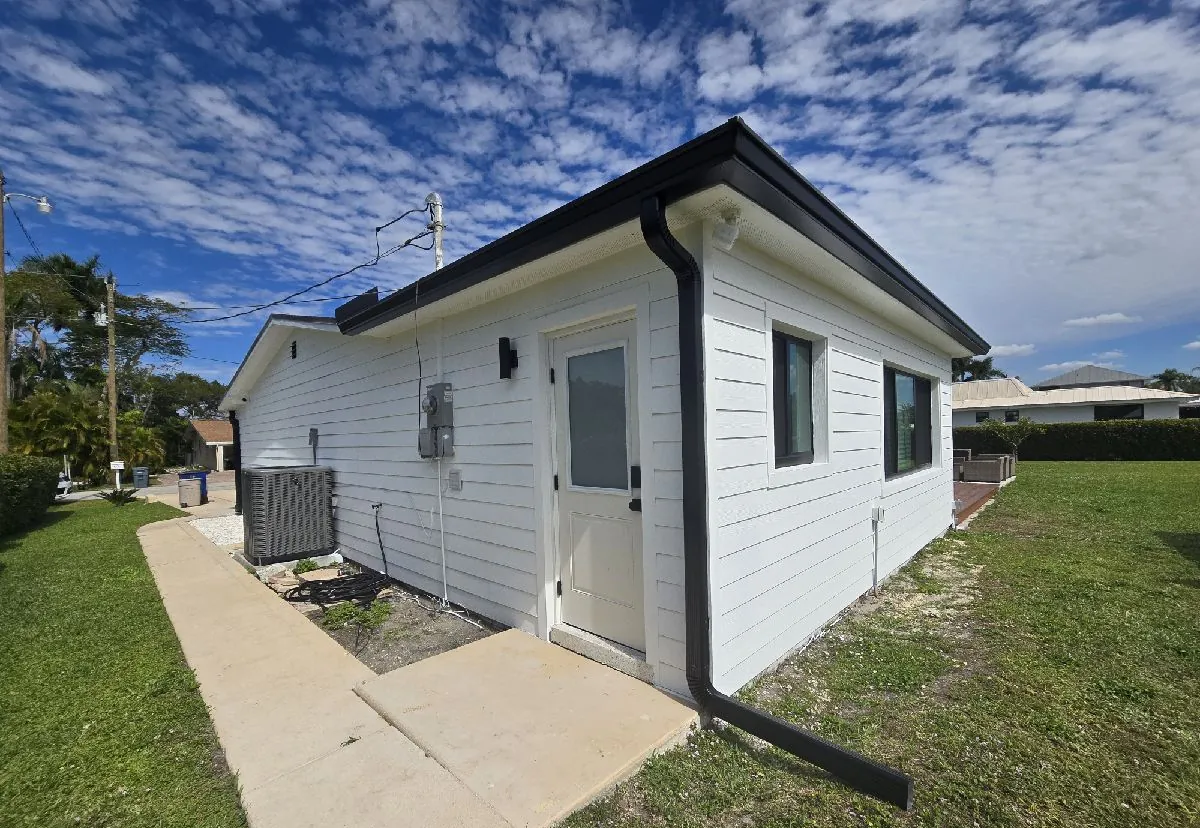White lap-siding home with black gutters and downspout in North Fort Myers, FL