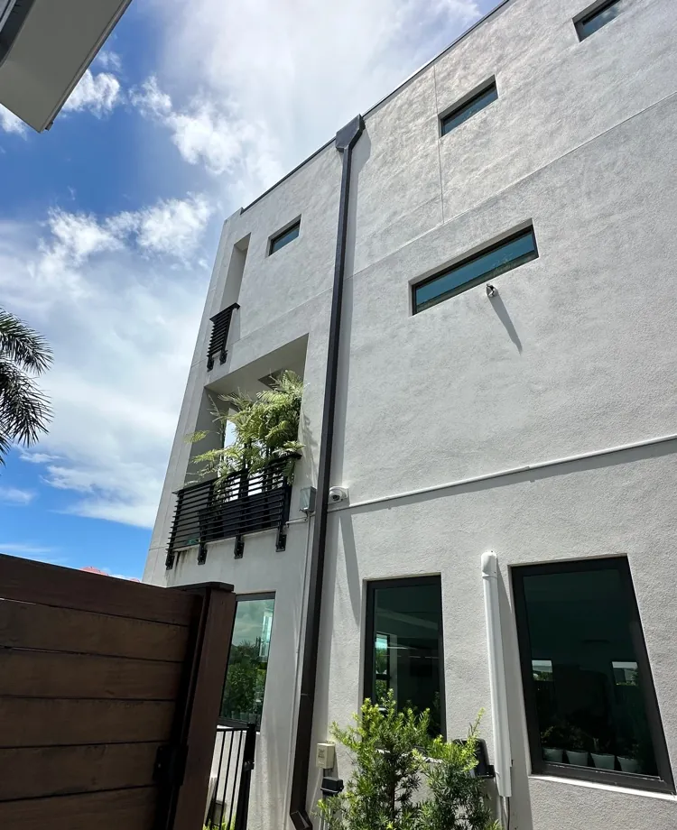 Gray modern stucco townhome with bronze downspouts in Fort Myers Beach, FL