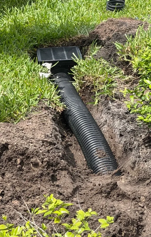 Corrugated drain pipe running into a square catch basin in an open trench in Lehigh Acres, FL