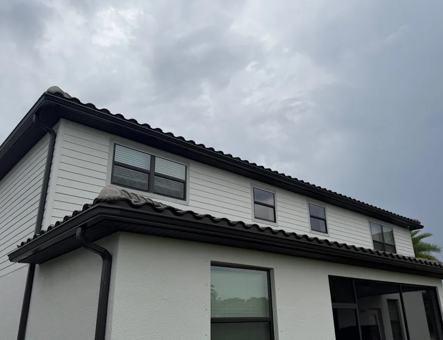 Two-story home with tile roof and dark bronze gutters on both roof levels in Fort Myers, FL