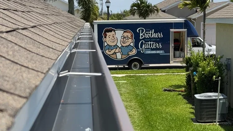 View down a newly installed seamless gutter with hidden hangers and the Brothers Gutters truck parked out front in Cape Coral, FL