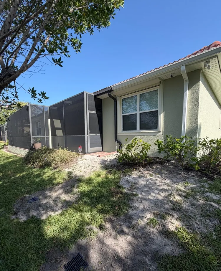 Home with downspouts piped underground to a drain grate in the side yard in Fort Myers, FL