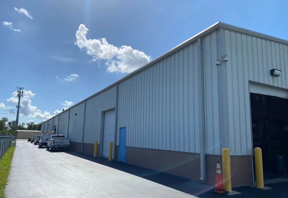 Long metal warehouse building with gutters and downspouts along the eave before service in Fort Myers, FL
