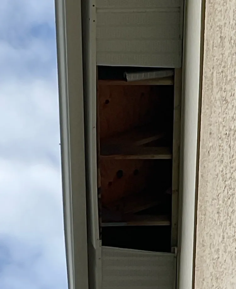 Gap from a missing soffit panel exposing the roof framing before repair in Cape Coral, FL