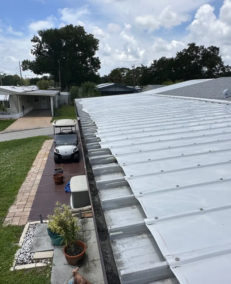 Old clogged roll-formed box gutter along a metal carport roof before replacement in North Fort Myers, FL