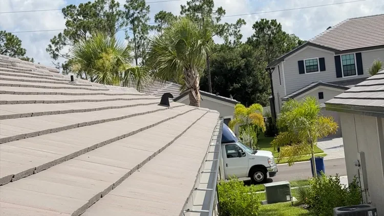 Crew member connecting a downspout below a newly installed gutter on a tile roof home in Fort Myers, FL