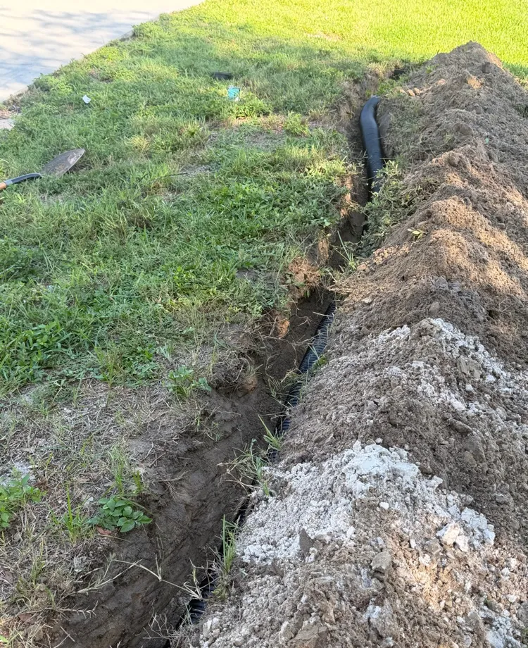Long trench through a lawn with 4-inch corrugated drain pipe laid in it in Fort Myers, FL