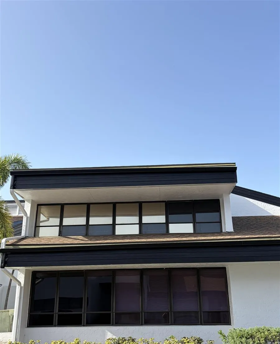 Undersized gutters hanging from rotted fascia on a two-story building in Fort Myers, FL