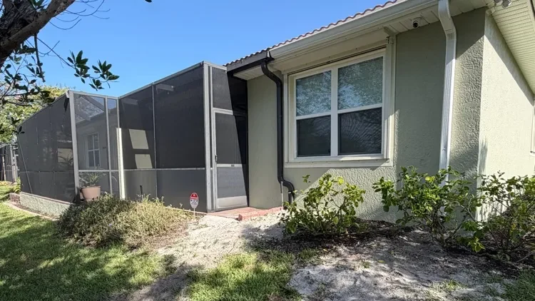 Home with downspouts piped underground to a drain grate in the side yard in Fort Myers, FL