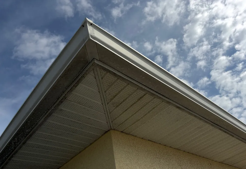 Weathered, stained soffit and fascia under a roof gable before replacement in Fort Myers Beach, FL