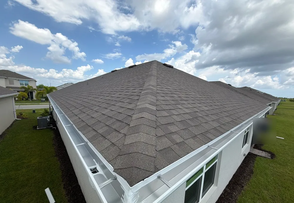 Elevated view of white gutters along a hip shingle roof in North Fort Myers, FL