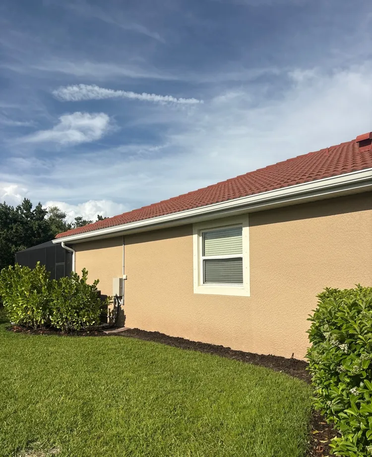 White gutters on a tan stucco home with a terracotta tile roof in North Fort Myers, FL