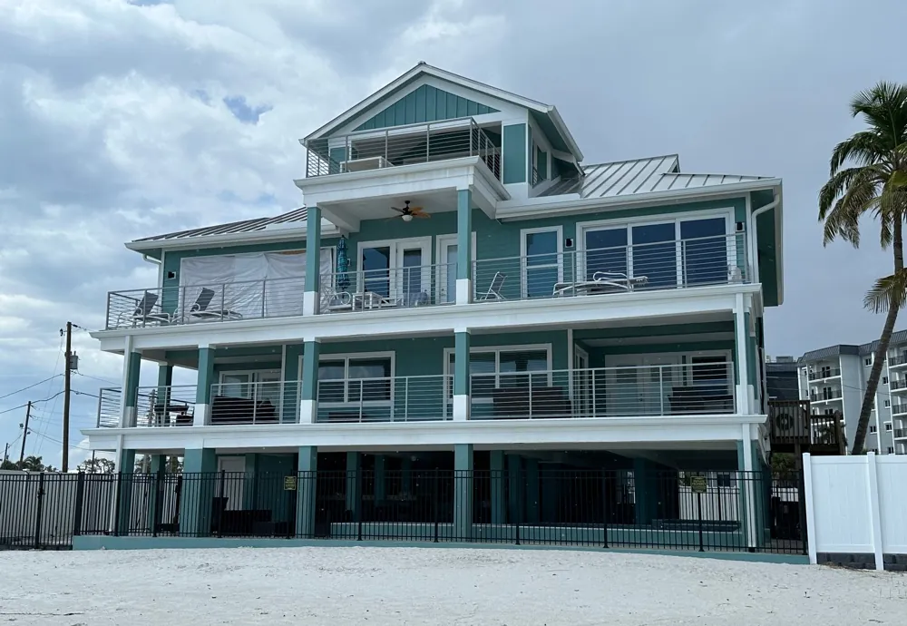 Teal three-story beachfront home with white gutters in Fort Myers Beach, FL