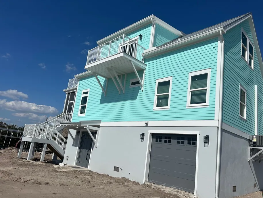Turquoise raised beach home with white gutters and downspouts in Fort Myers Beach, FL