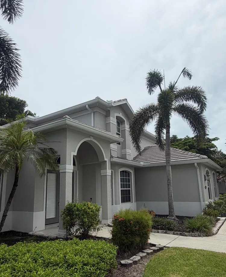 Two-story Naples home with arched entry, tile roof and white seamless gutters