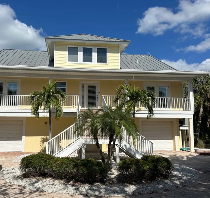 Yellow elevated home with white gutters and a metal roof in Sanibel, FL