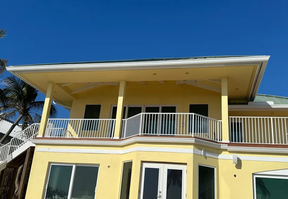 Yellow Gulf-front home with white gutters above the balcony in Sanibel, FL