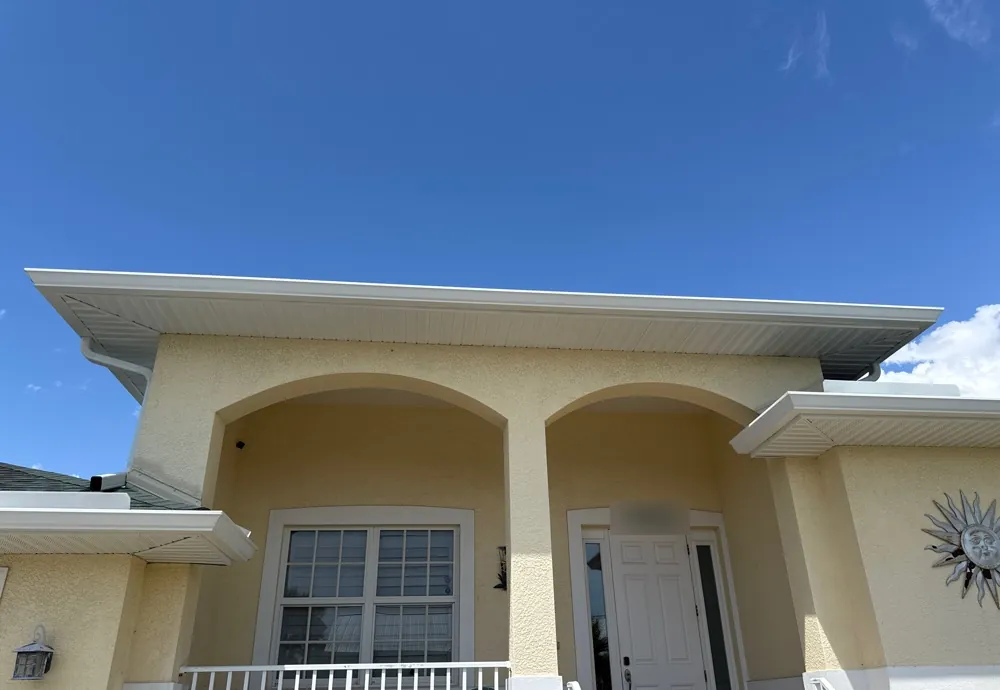 Yellow stucco home with arched entry and white gutters in Fort Myers Beach, FL