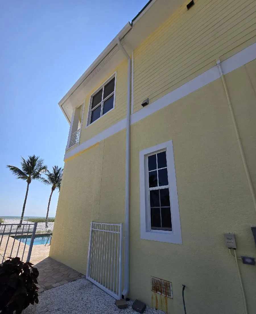 Yellow two-story home with a white downspout in Fort Myers Beach, FL